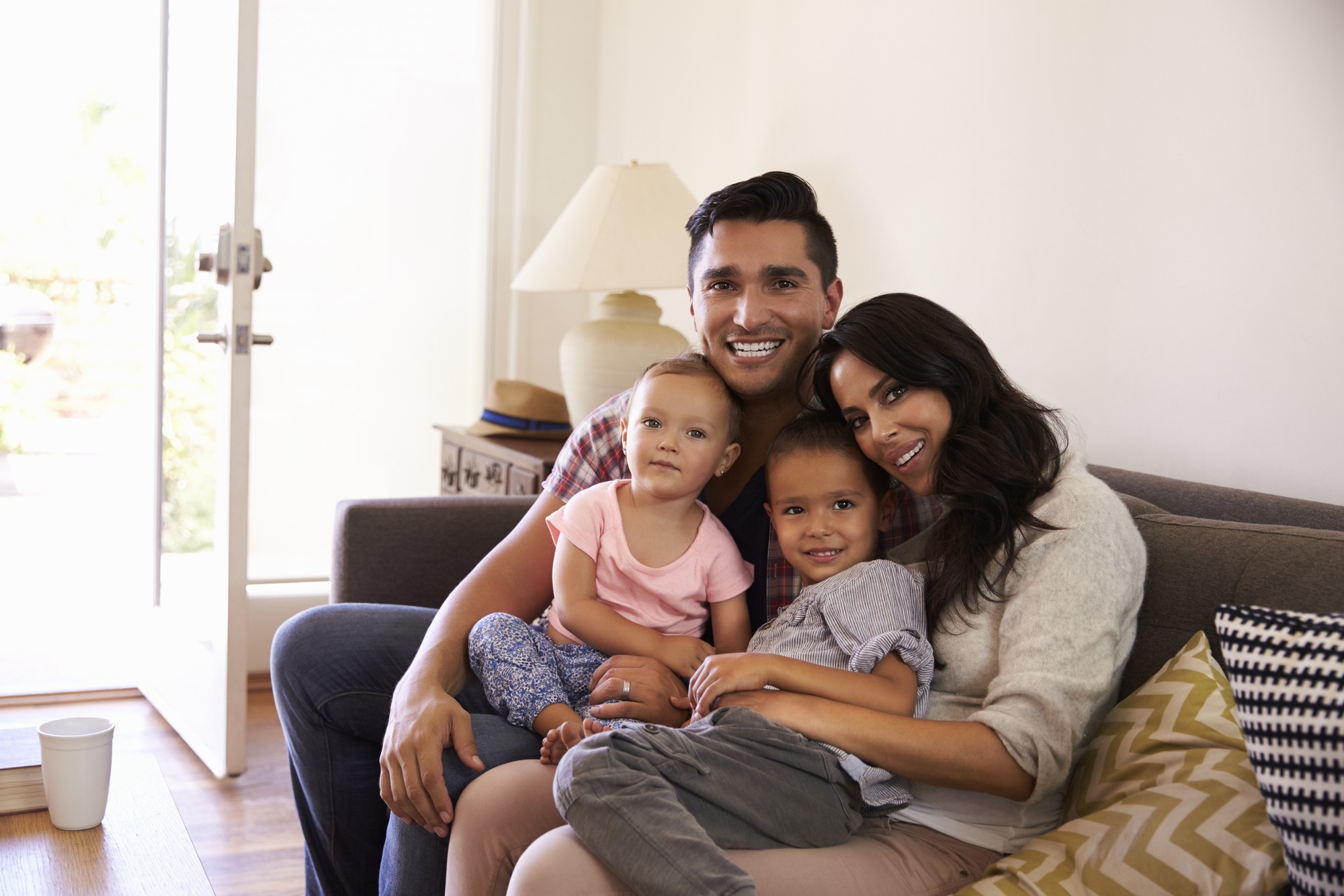 Portrait Of Happy Family Sitting On Sofa In at Home.